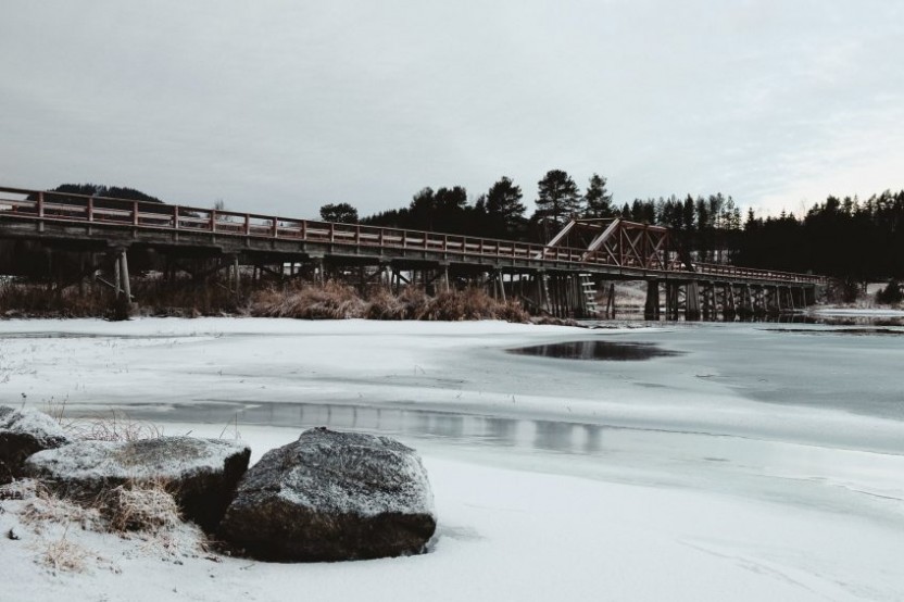 Bild föreställandes Vikbron, en träbro som går över älven Ljungan, med stenar i förgrunden
